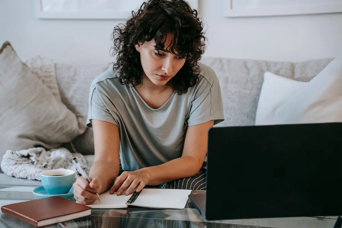 Job seeker writing her tell me about yourself answer in a notebook